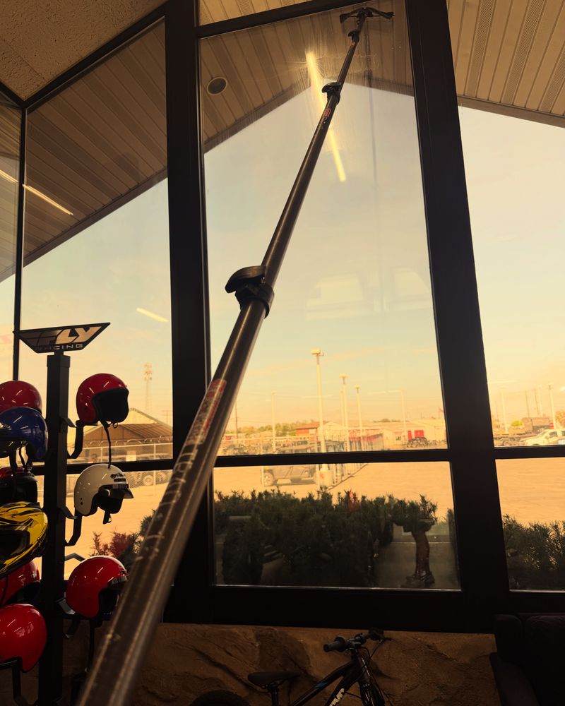 Sunset through clean showroom glass, with a water-fed pole in the foreground