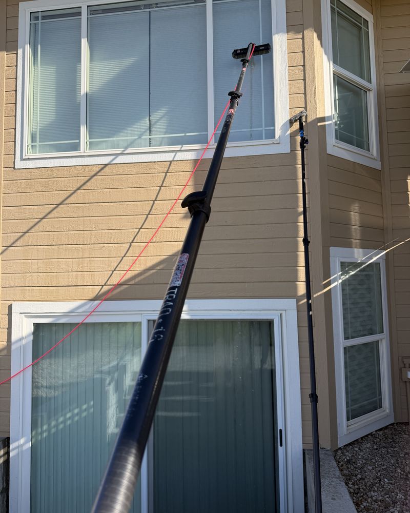 Water-fed pole cleaning the upper windows of a two-story home